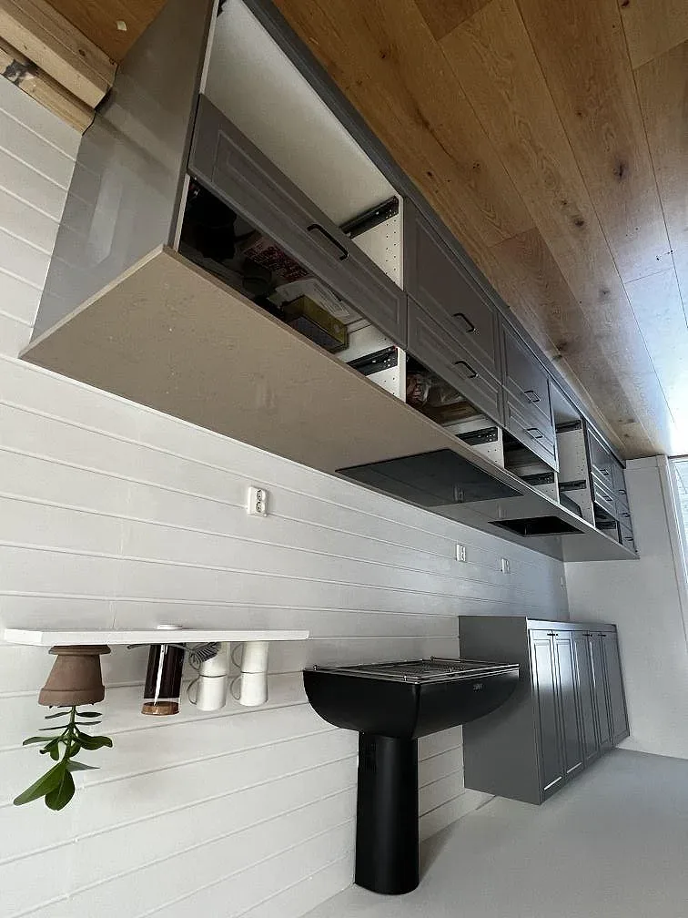 Lång köksbänk i lergrå Silestone Coral Clay längs köksväggen, med köksfläkt och grå skåp under montering i Kungsbacka.