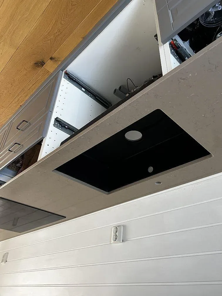Köksbänk i Silestone Coral Clay med urtag för diskho och en infälld svart induktionshäll under pågående montering i Kungsbacka.