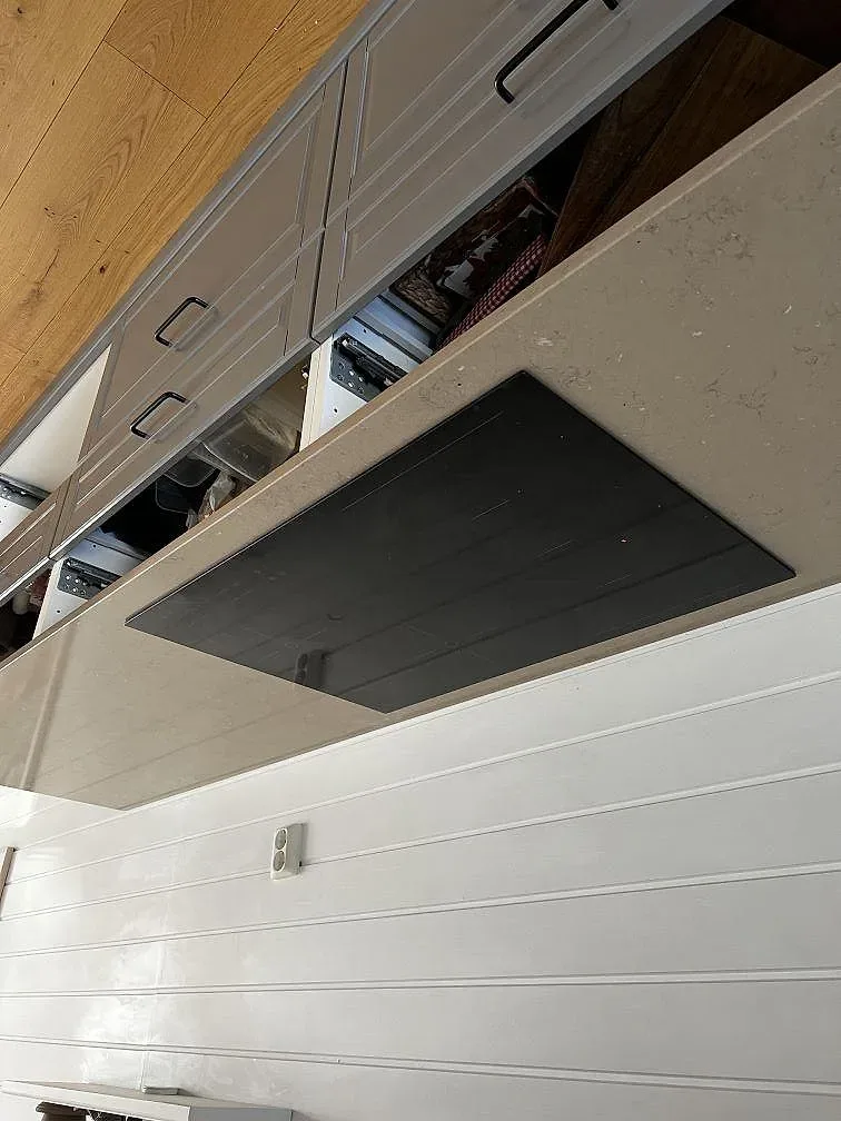 Svart induktionshäll infälld i lergrå Silestone Coral Clay-bänkskiva sedd snett ovanifrån i ett kök i Kungsbacka.
