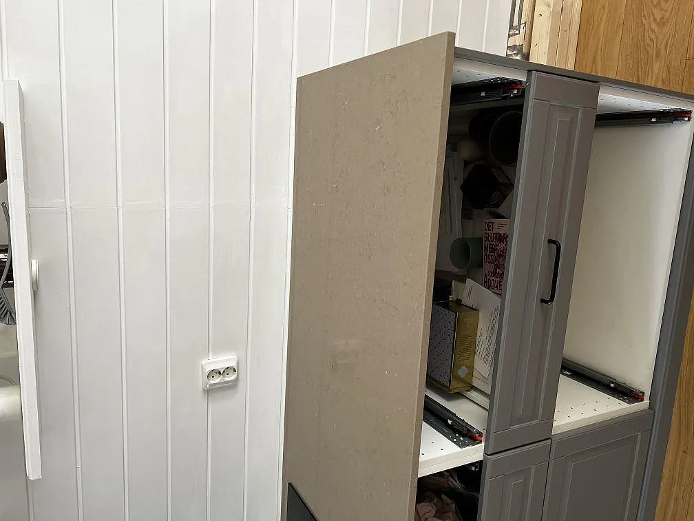 Stensida i Silestone Coral Clay som klär köksskåpets gavel mot vit pärlspontvägg i Kungsbacka.