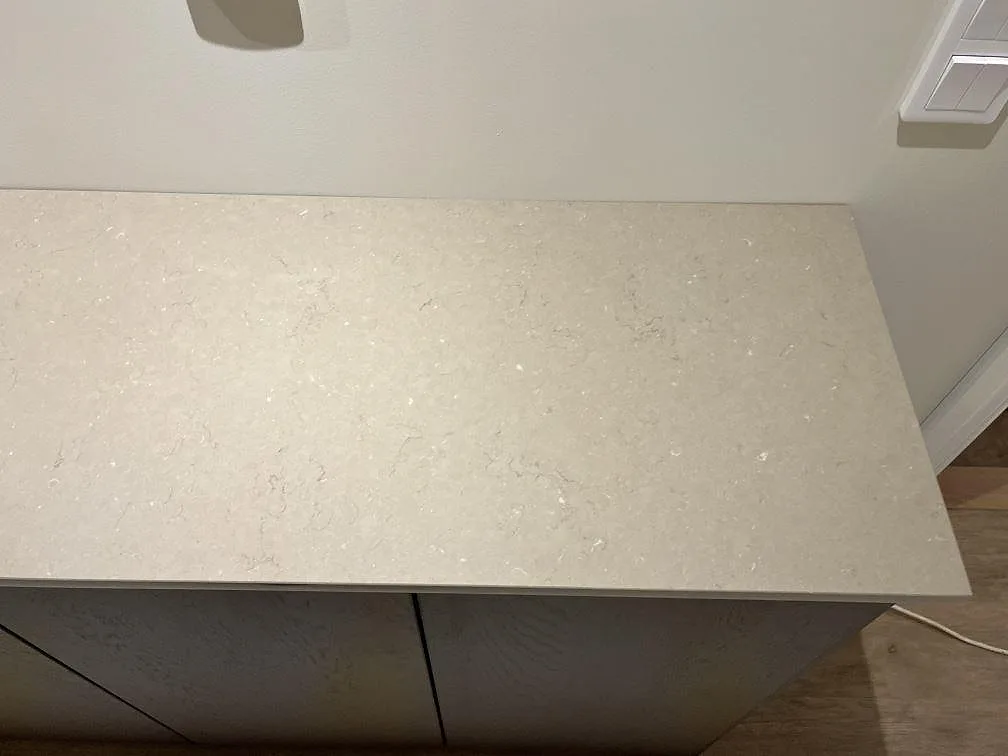 Polerad köksbänk i Silestone Coral Clay med tydlig spegelreflex och fin kvartsådring i ett kök i Kungshamn.