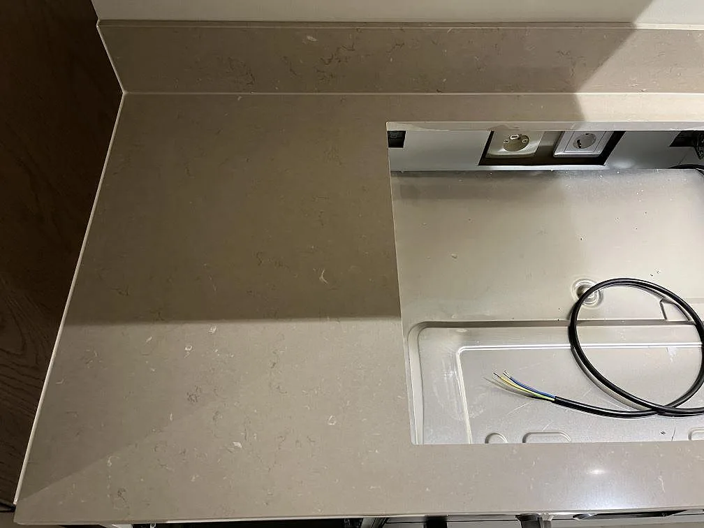 Polerad köksbänkskiva i Silestone Coral Clay sedd ovanifrån med urtag för övermonterad häll och eluttag i ett kök i Kungshamn.