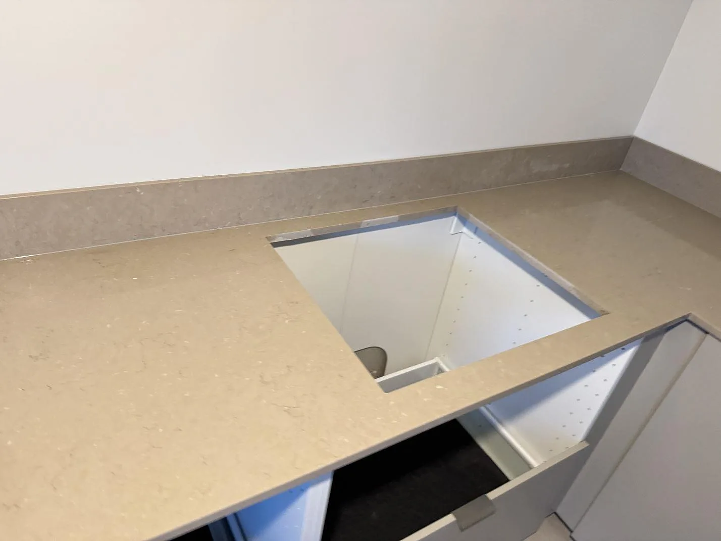 Polerad bänkskiva i Silestone Coral Clay med rektangulär hällöppning och uppvikt stänkkant i ett kök i Länghem.