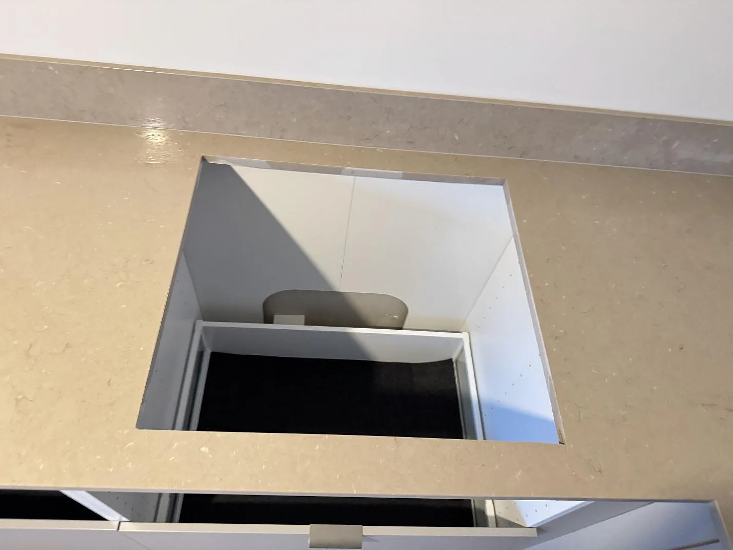 Detalj av hällöppning i polerad Silestone Coral Clay, monterad som köksbänkskiva med matchande stänkkant i Länghem.