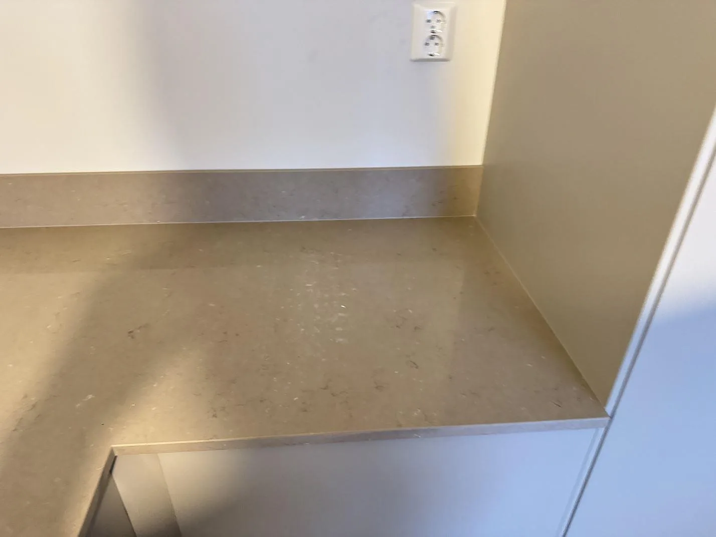 Rak väggbänk i polerad Silestone Coral Clay, varm gråbeige kvartskomposit med låg stänkkant i ett kök i Länghem.