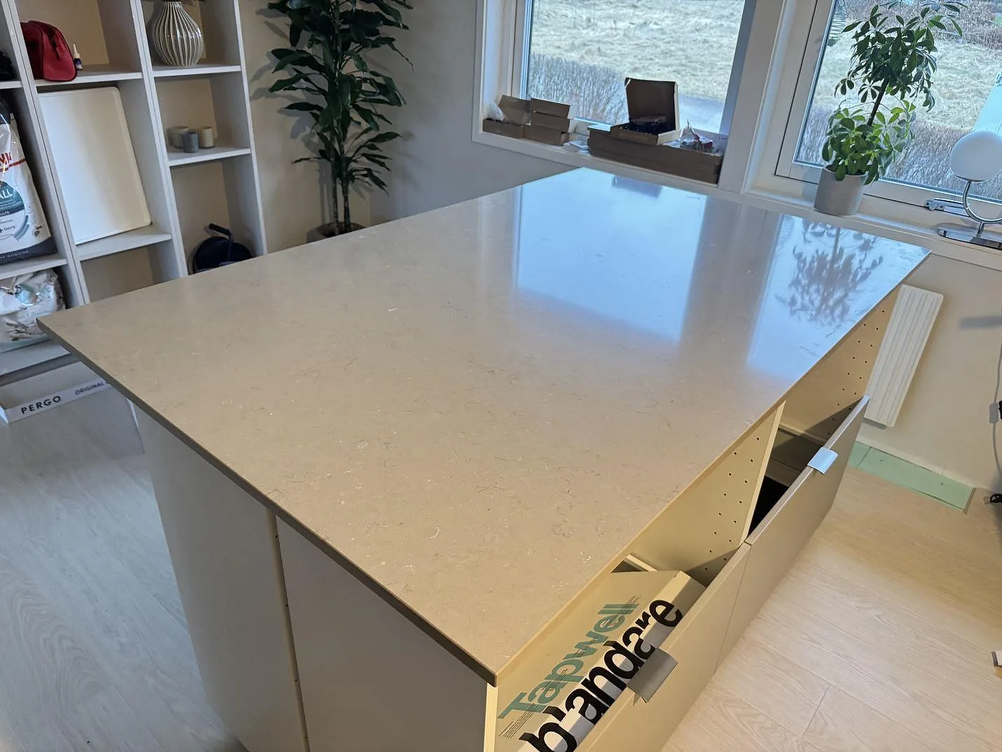 Polerad köksö i Silestone Coral Clay med ljus gråbeige kompositsten och öppna köksstommar i ett kök i Länghem.