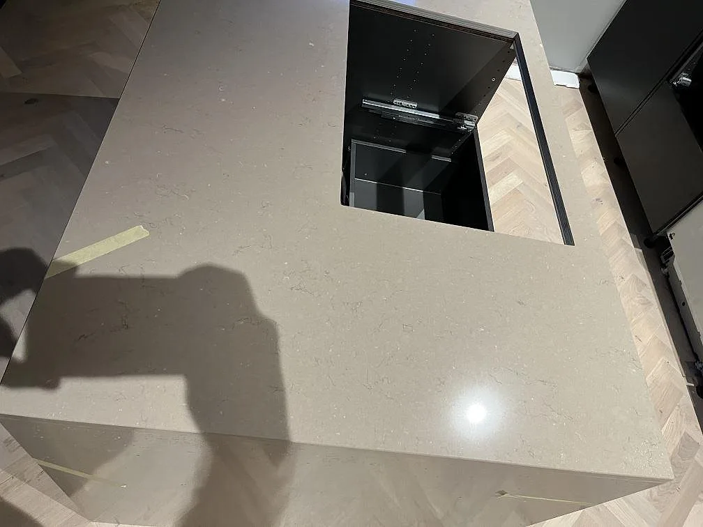 Polerad köksö i Silestone Coral Clay med hällurtag och sten som löper ner längs gavlarna, fotograferad under montering i ett kök i Landskrona.