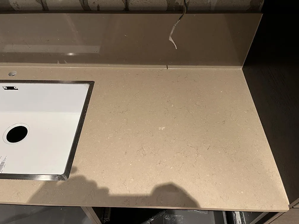 Köksö i polerad Silestone Coral Clay med nedsänkt hällurtag, sedd ovanifrån i ett kök under montering i Landskrona.