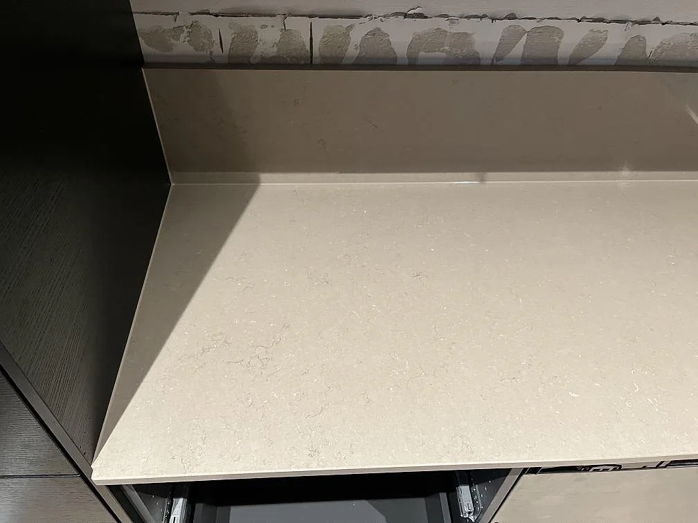 Köksbänkskiva i Silestone Coral Clay med uppvikt stänkskydd mot vägg, tagen under montering i ett kök i Landskrona.