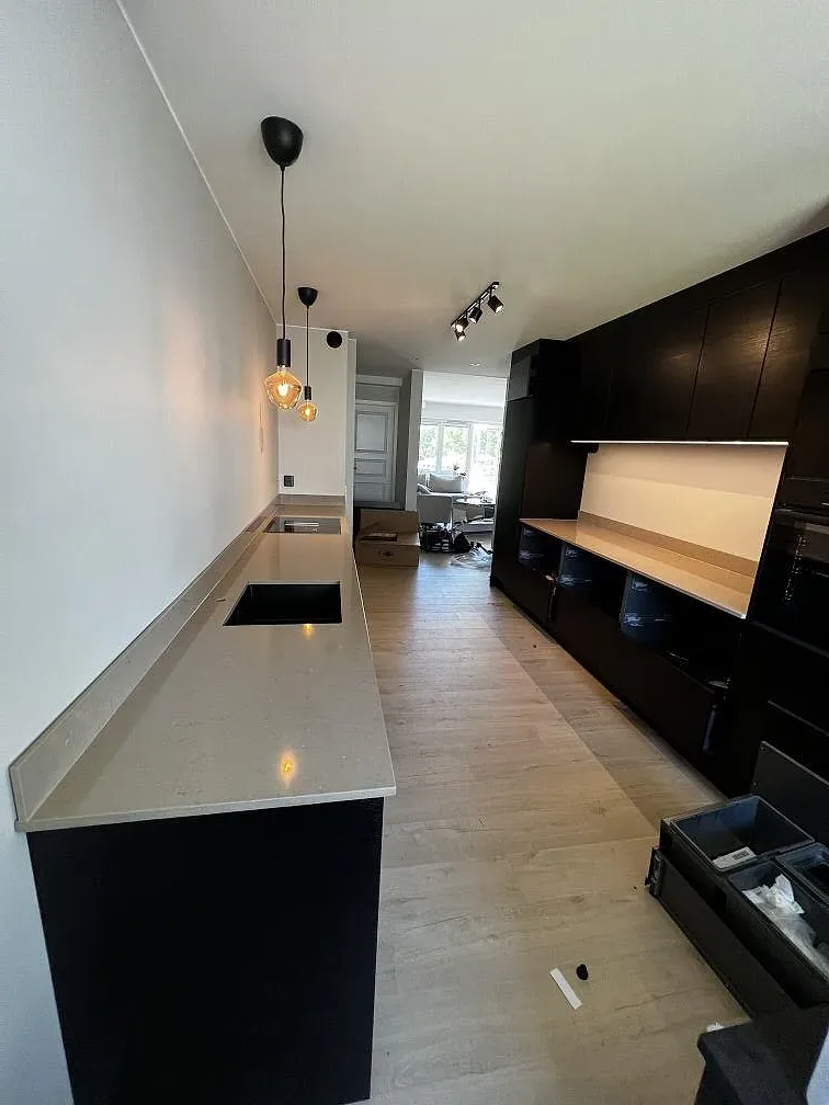 Polerad köksbänkskiva i Silestone Coral Clay med svart underlimmad diskho och svart häll i ett kök i Landskrona.