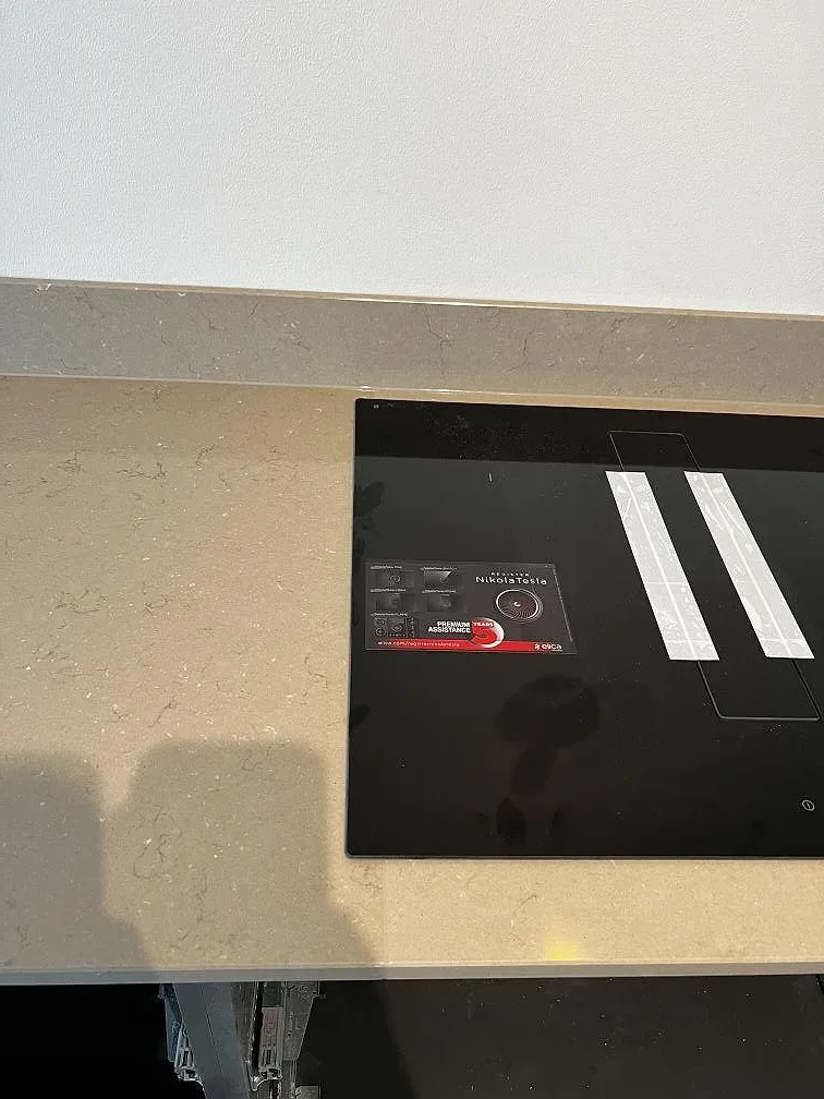 Närbild på polerad Silestone Coral Clay runt svart induktionshäll och gråbeige stänkkant i Landskrona.