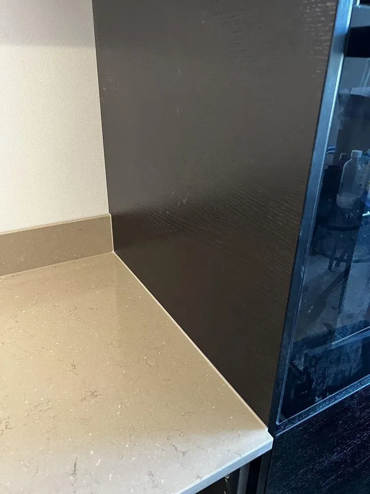 Hörn mot svart köksinredning med polerad Silestone Coral Clay och uppvikt stänkkant i Landskrona.