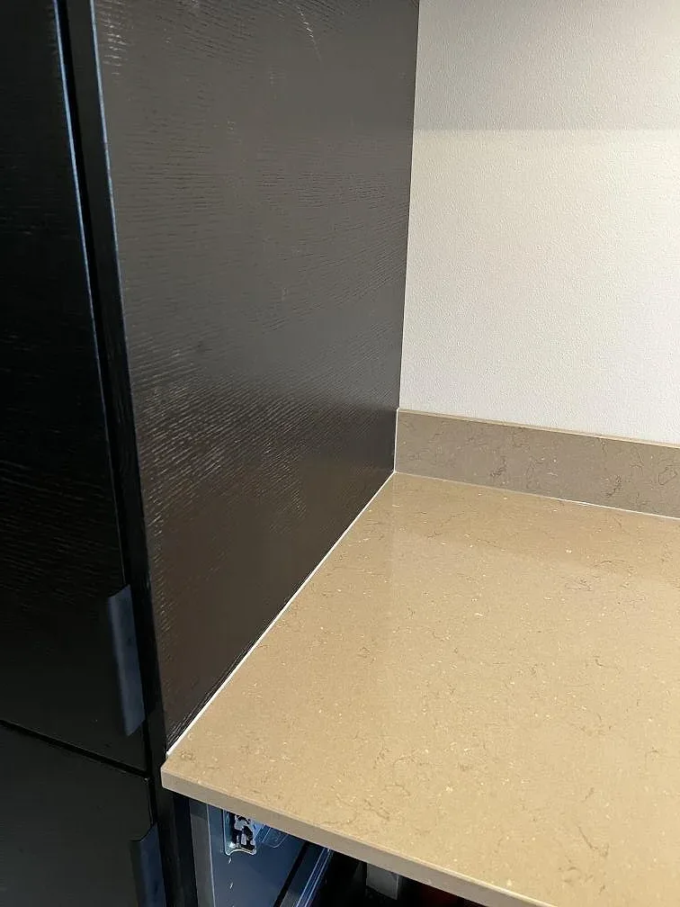 Detalj av polerad Silestone Coral Clay mot svart stomme och vit vägg i ett kök i Landskrona.