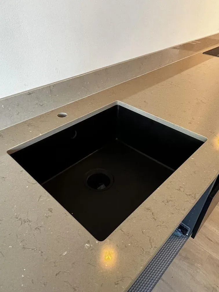 Svart underlimmad diskho i polerad Silestone Coral Clay med uppvikt stänkkant i ett kök i Landskrona.