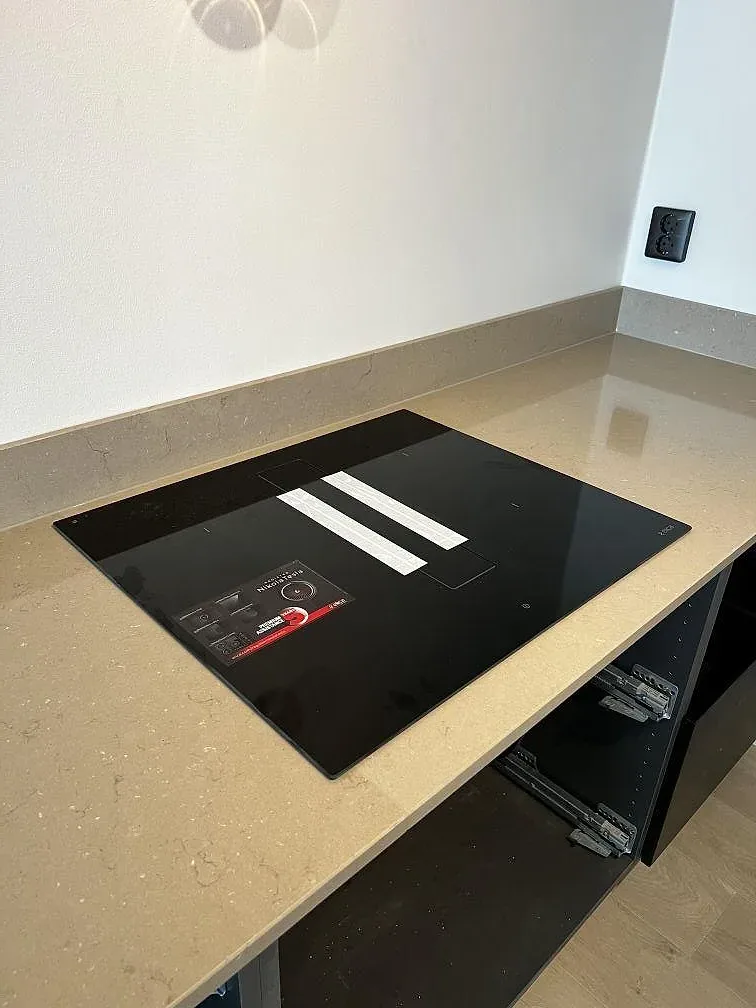 Svart induktionshäll infälld i polerad Silestone Coral Clay med låg stänkkant i Landskrona.