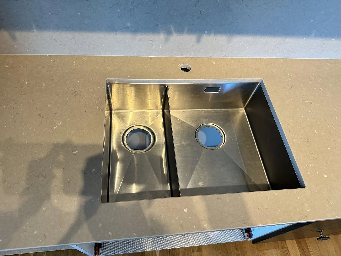 Detalj av underlimmad dubbel diskho i rostfritt stål monterad i polerad Silestone Coral Clay i Landskrona.