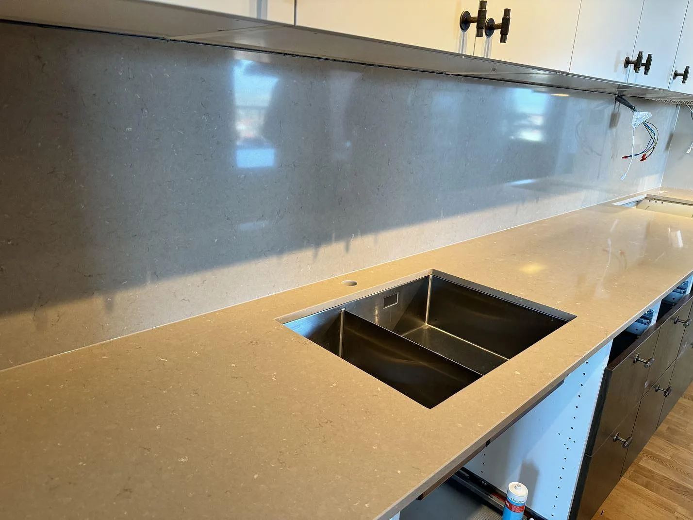 Lång köksbänkskiva i polerad Silestone Coral Clay med rostfri dubbelho och högt stänkskydd i ett kök i Landskrona.