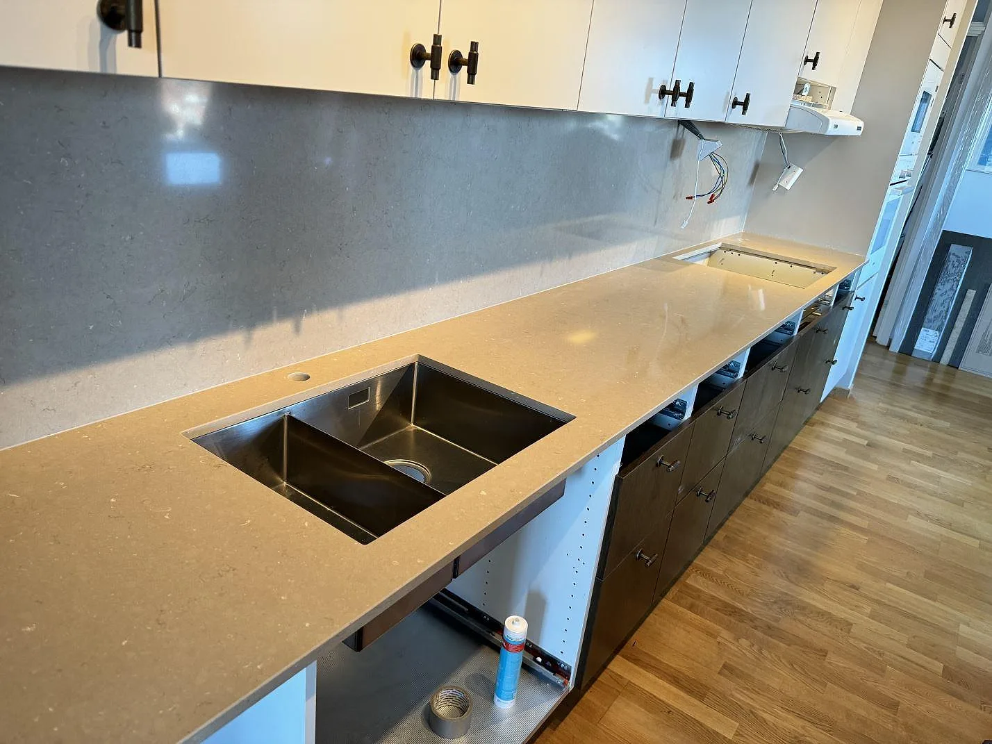Köksbänkskiva i polerad komposit, Silestone Coral Clay, med underlimmad dubbel diskho och grå stänkskyddsvägg i Landskrona.