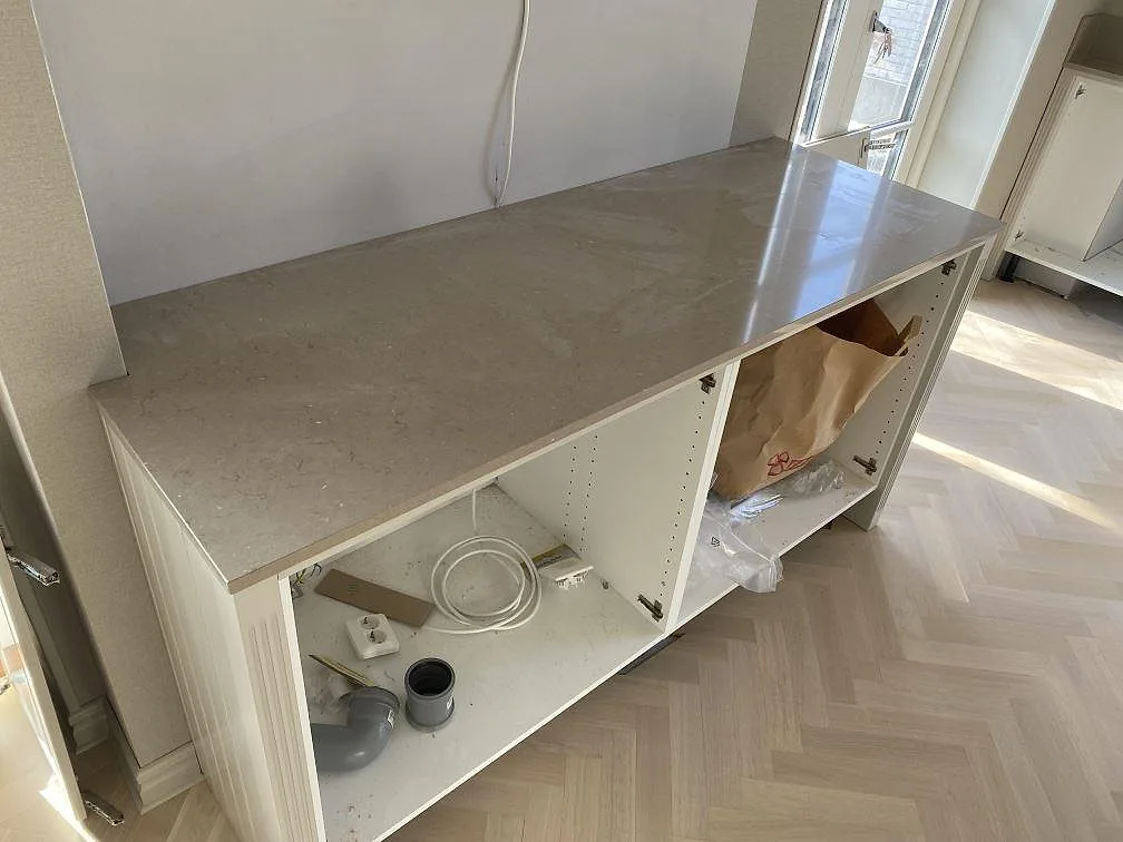 Sidobänk i polerad Silestone Coral Clay på vita köksstommar, fotograferad under montering i Landskrona.