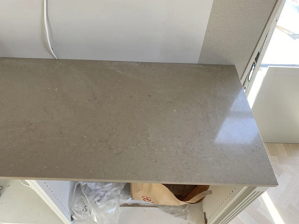 Närbild på polerad Silestone Coral Clay kompositbänkskiva med varm beigegrå ton och ljusreflex i Landskrona.