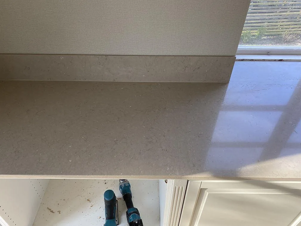 Närbild på polerad Silestone Coral Clay bänkskiva vid fönster med matchande stänkskydd och mjuka ljusreflexer i Landskrona.