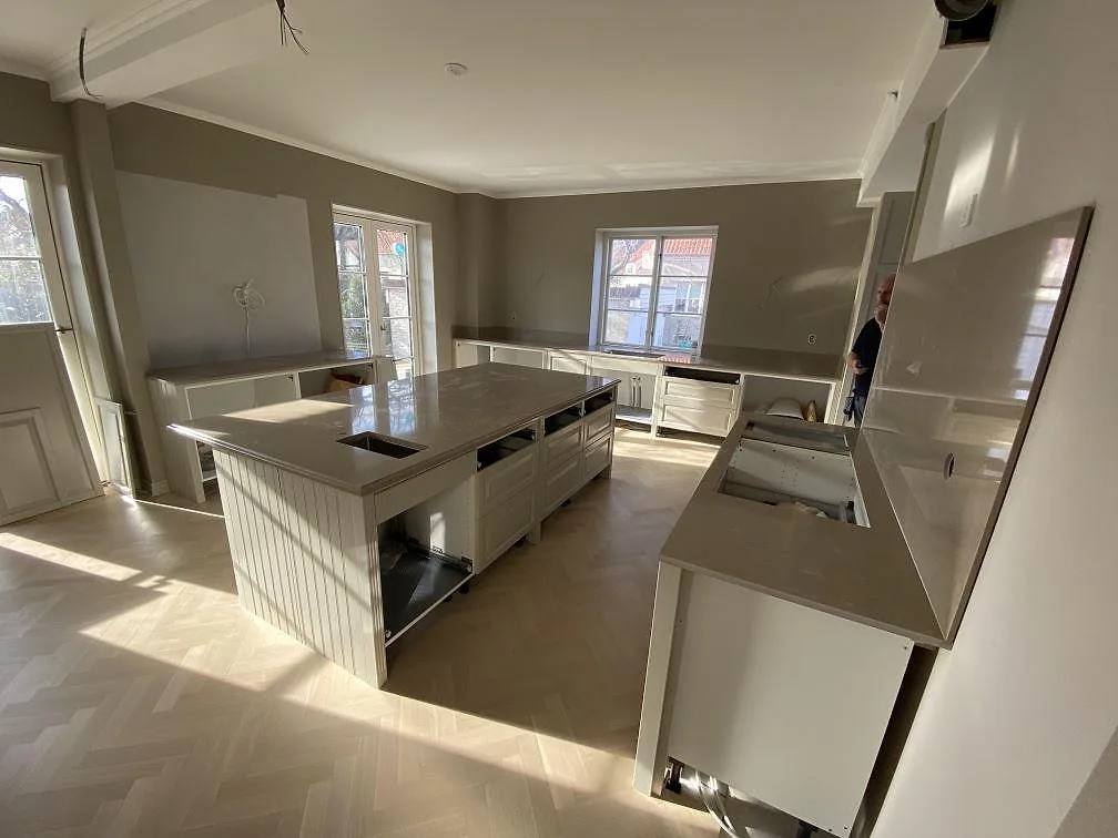 Brett monteringsfoto av kök i Landskrona med polerad Silestone Coral Clay på köksö, bänkskivor och stänkskydd i samma greige komposit.