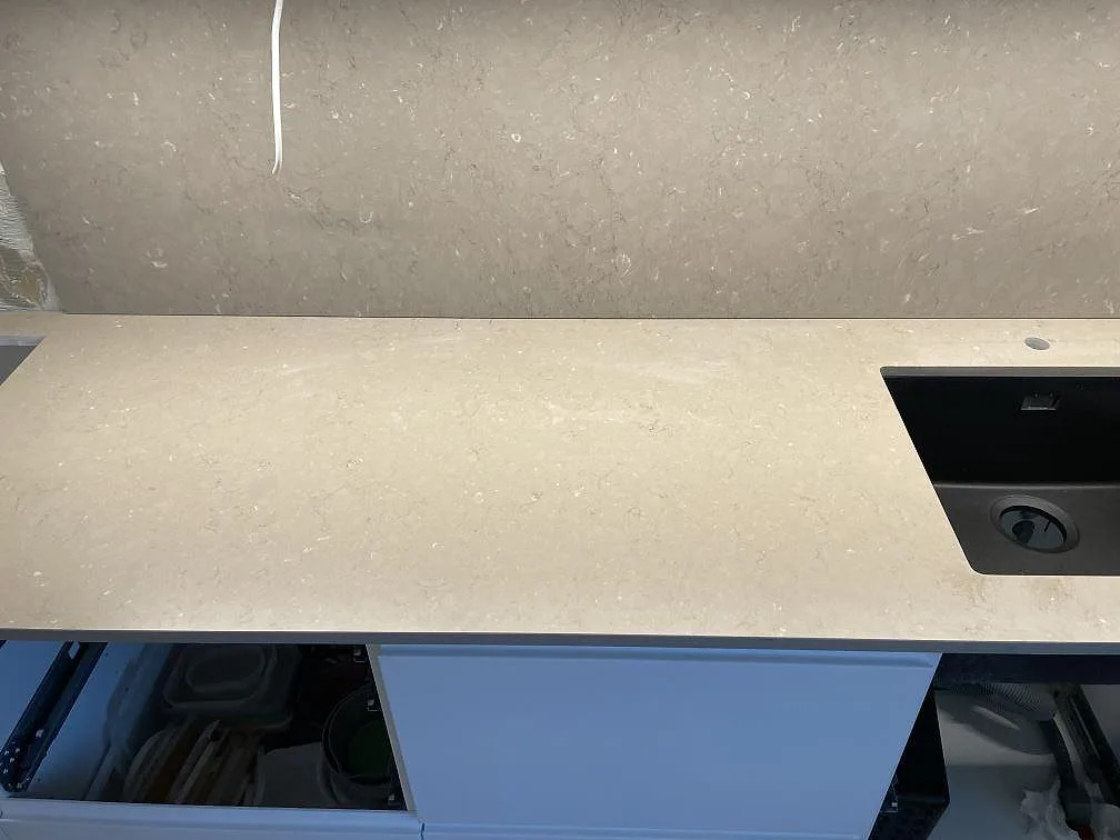 Arbetsyta i matt Silestone Coral Clay, beige kvartskomposit, med synlig mineralteckning och del av svart diskho i Landskrona.