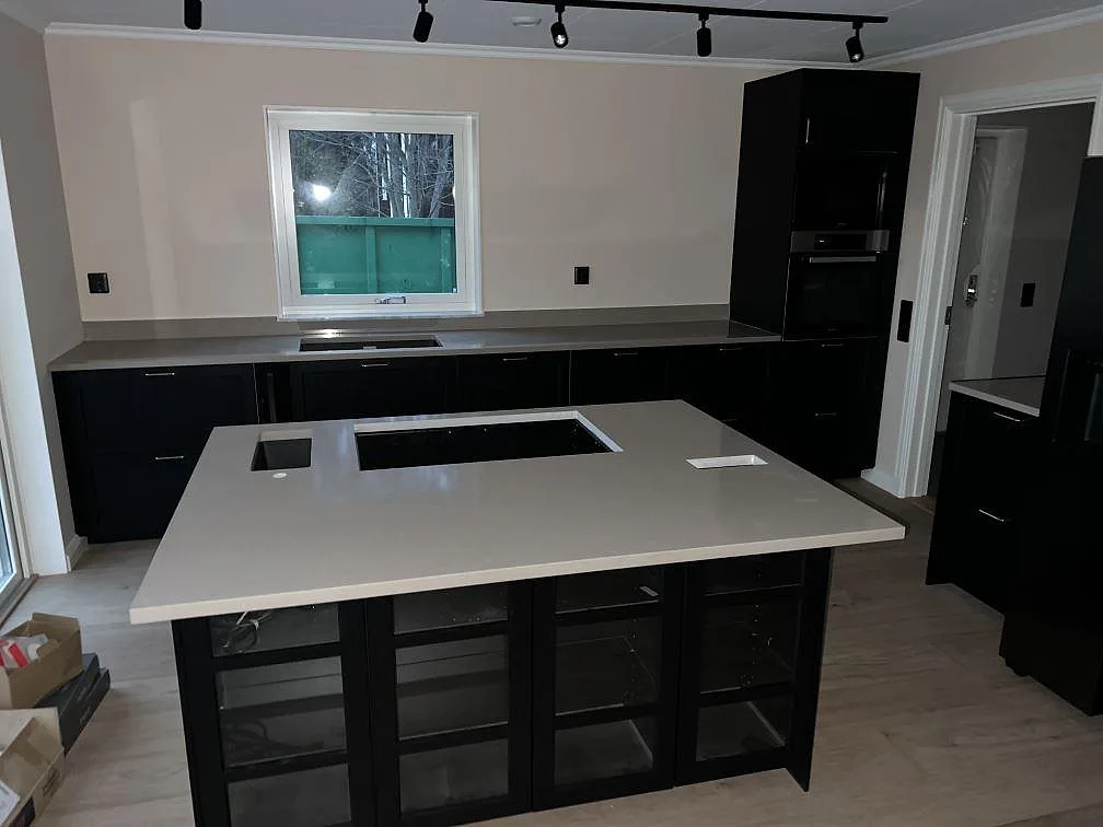 Köksbänkskiva i polerad Silestone Coral Clay komposit, med köksö och bänkrad under fönster i ett kök i Leksand.