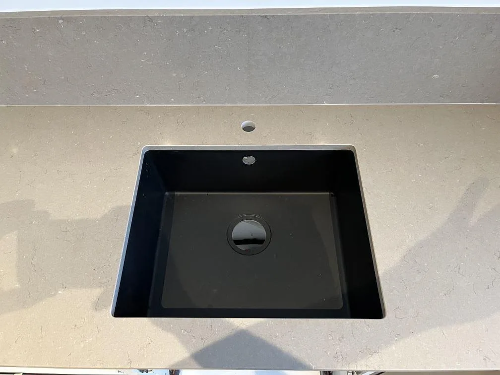 Närbild på underlimmad svart kompositdiskho i polerad Silestone Coral Clay köksbänkskiva i Limhamn.