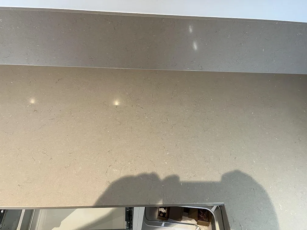 Polerad Silestone Coral Clay bänkskiva med uppvikt stänkkant och mjuk ådring i ett kök i Limhamn.