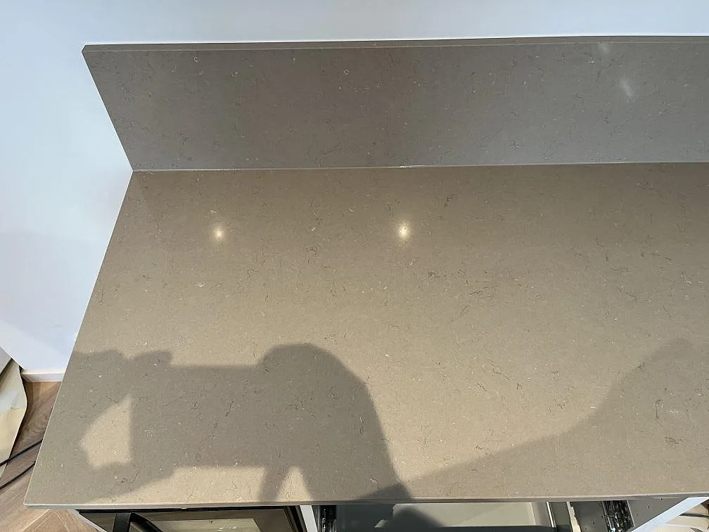 Köksbänkskiva i Silestone Coral Clay, polerad varm taupe kvartskomposit, med uppvikt stänkkant i ett kök i Limhamn.
