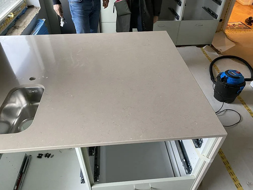 Köksö i Silestone Coral Clay sett ovanifrån med underlimmad rostfri diskho i ett kök under montering i Limhamn.