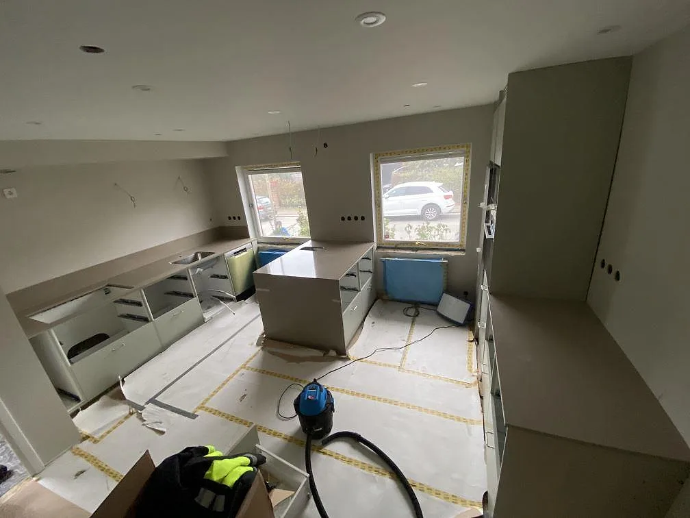 Översikt över ett kök i Limhamn under montering med köksö och bänkskivor i polerad Silestone Coral Clay.