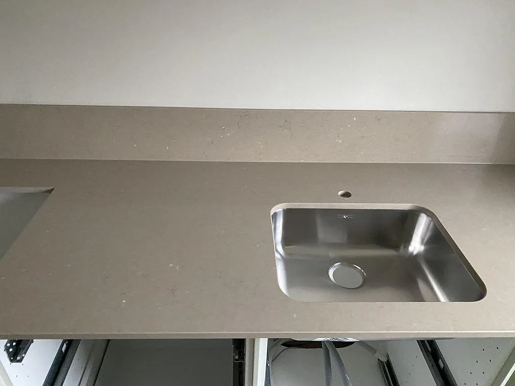 Polerad bänkskiva i Silestone Coral Clay med en större underlimmad rostfri diskho och rent stänkskydd i ett kök i Limhamn.