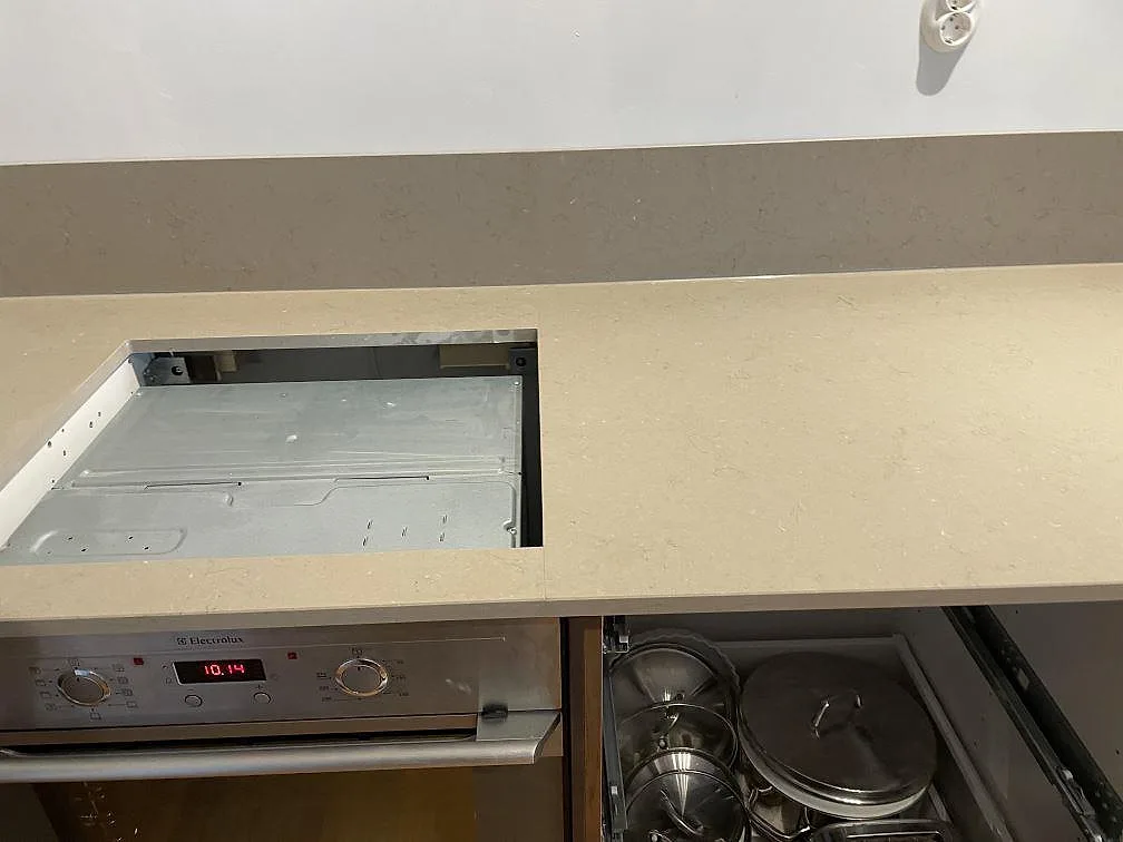 Köksbänkskiva i Silestone Coral Clay, matt Mocka, med förberett hälluttag ovanför rostfri ugn i ett kök under montering i Limhamn.