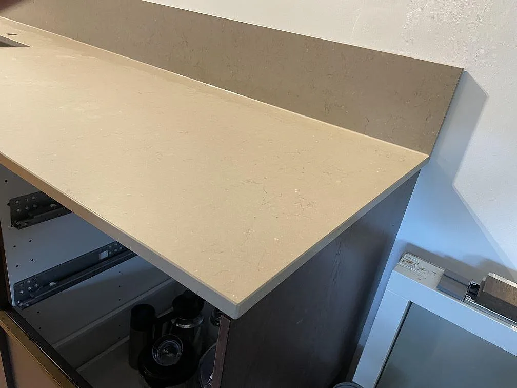 Detalj av köksbänkskiva i Silestone Coral Clay, matt Mocka, med 12 mm stänkskydd i samma komposit och öppen stomme i Limhamn.