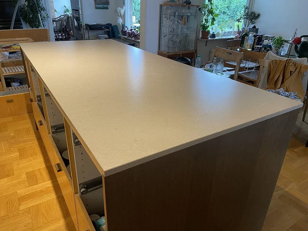 Stor köksö i Silestone Coral Clay, matt Mocka-yta i varm gråbeige ton, monterad på mörk och träfärgad köksö i Limhamn.