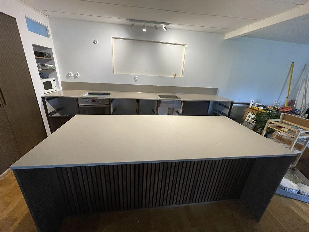 Köksbänkskiva och stor köksö i Silestone Coral Clay, matt Mocka-yta, med ribbad mörk ösida och väggbänk i ett kök i Limhamn.
