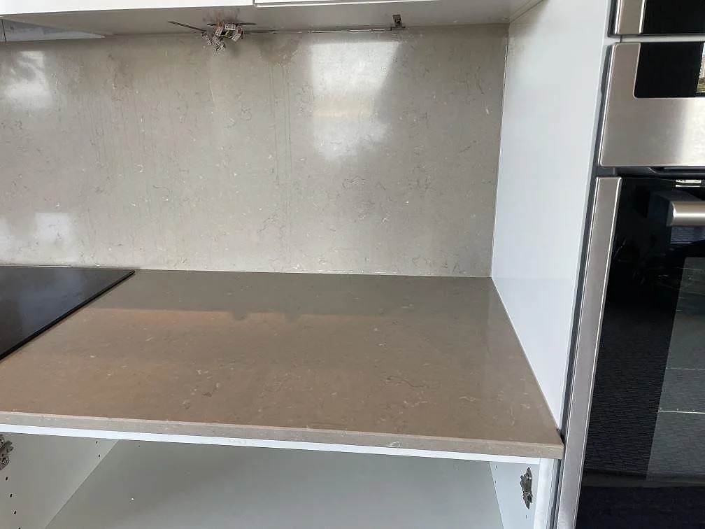 Närbild på polerad Silestone Coral Clay som köksbänkskiva och stänkskydd vid hällzonen i Limhamn.