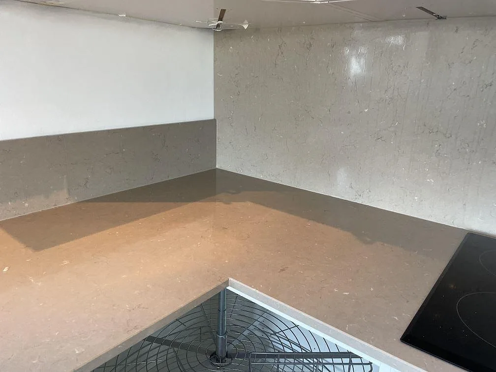 Polerad köksbänkskiva i Silestone Coral Clay med varm gråbeige ton, L-hörn, stänkskydd och svart häll i Limhamn.
