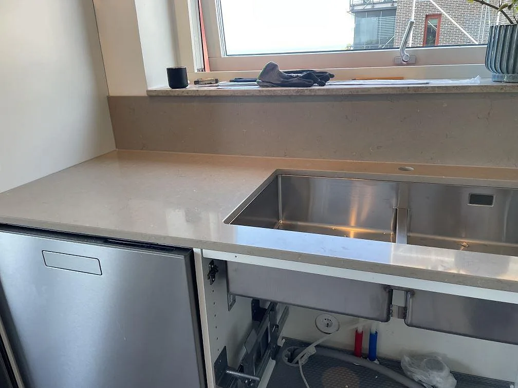 Diskzon i Limhamn med polerad Silestone Coral Clay, underlimmad rostfri diskho, låg stänkkant och fönsterbänk i samma kompositsten.