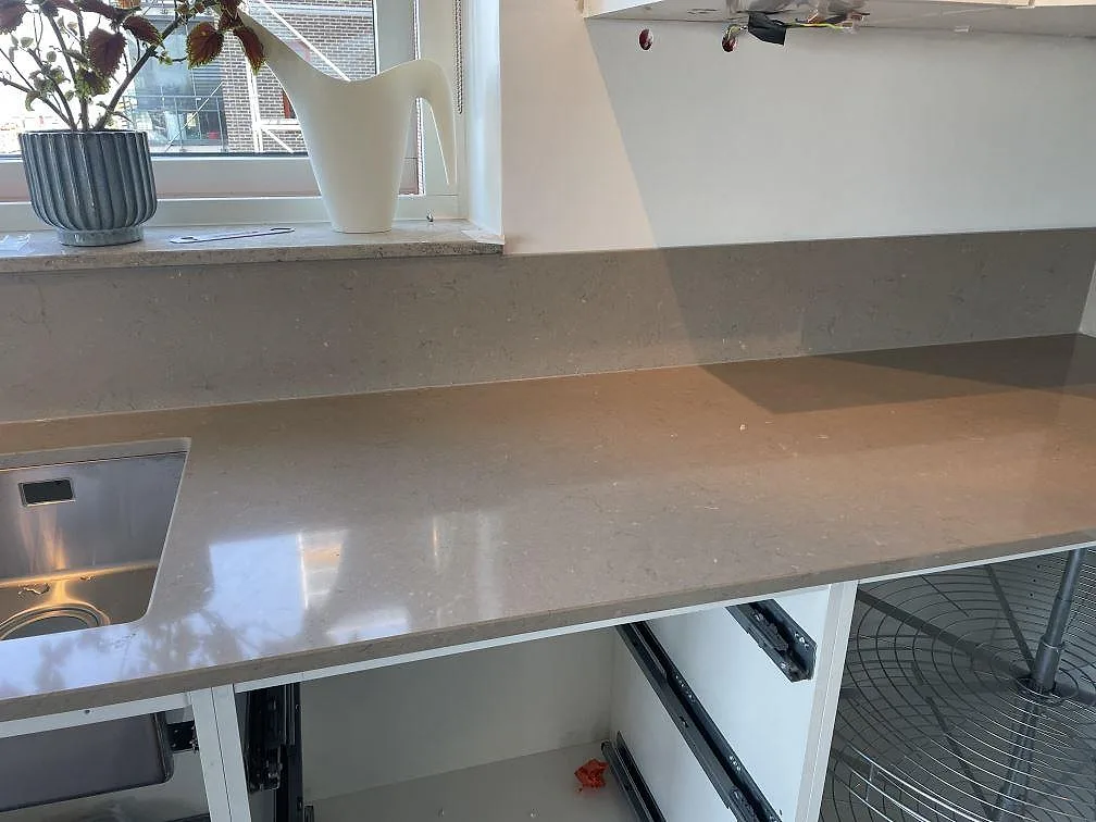 Köksbänkskiva i polerad Silestone Coral Clay med underlimmad rostfri diskho, fönsterbänk och stänkskydd i ett kök i Limhamn.