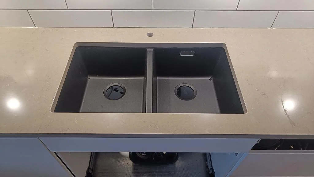 Närbild på svart dubbelho i bänkskiva av polerad Silestone Coral Clay, kvartskomposit, i köket i Limhamn.