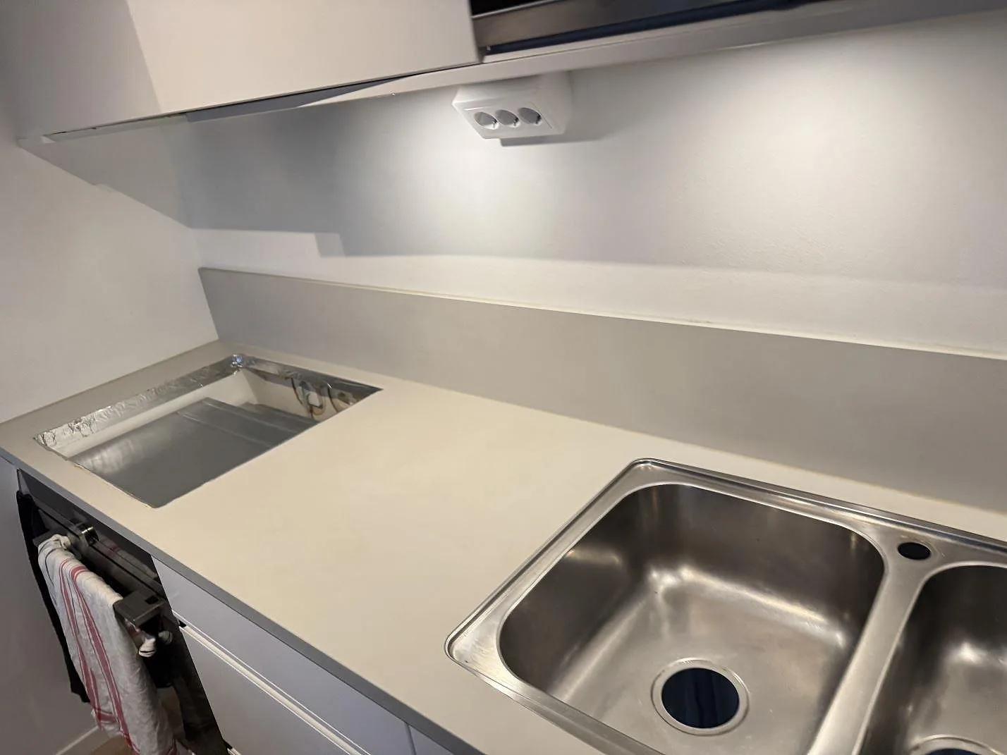 Polerad köksbänkskiva i Silestone Coral Clay med rostfri diskho och hällöppning under montering i Limhamn.