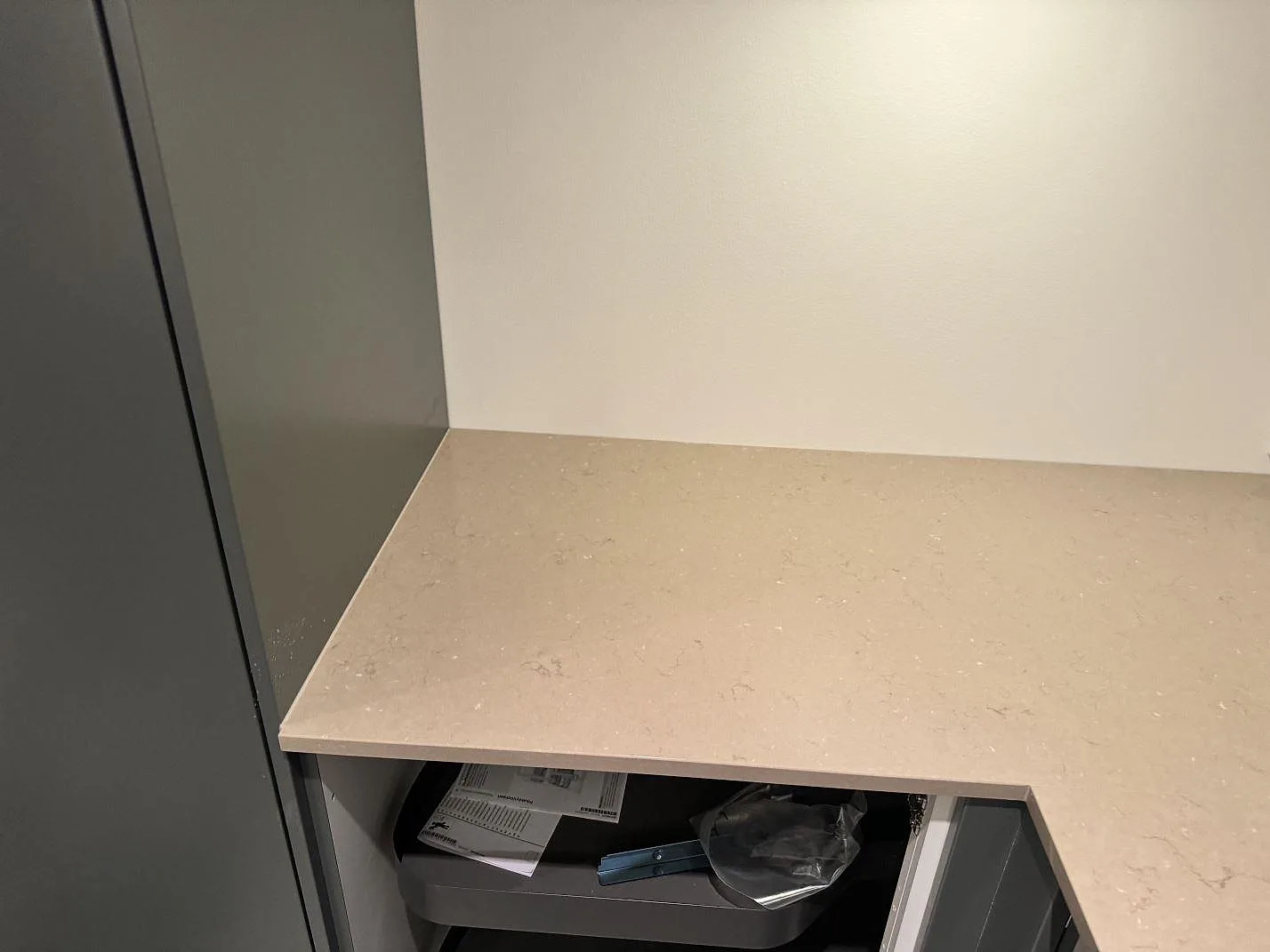 Närbild på köksbänkskiva i polerad Silestone Coral Clay över öppna köksstommar under montering i Löddeköpinge.