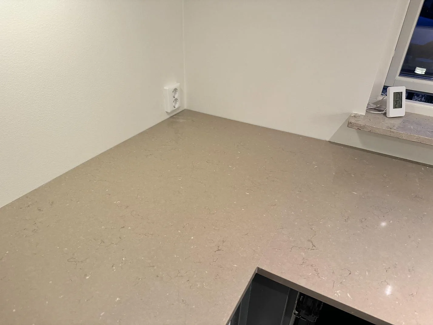 Bred vy över polerad Silestone Coral Clay som köksbänkskiva med fönsterbänk i samma kvartskomposit i Löddeköpinge.