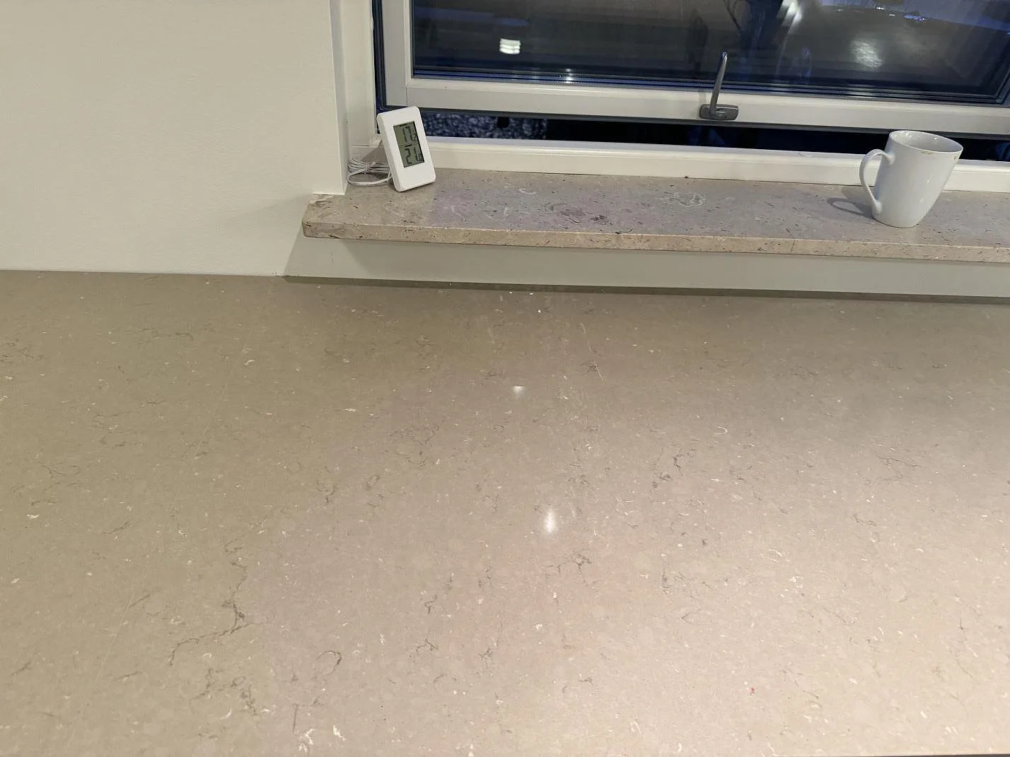 Detalj av polerad Silestone Coral Clay framför fönsterbänk med varm gråbeige kvartskomposit i Löddeköpinge.