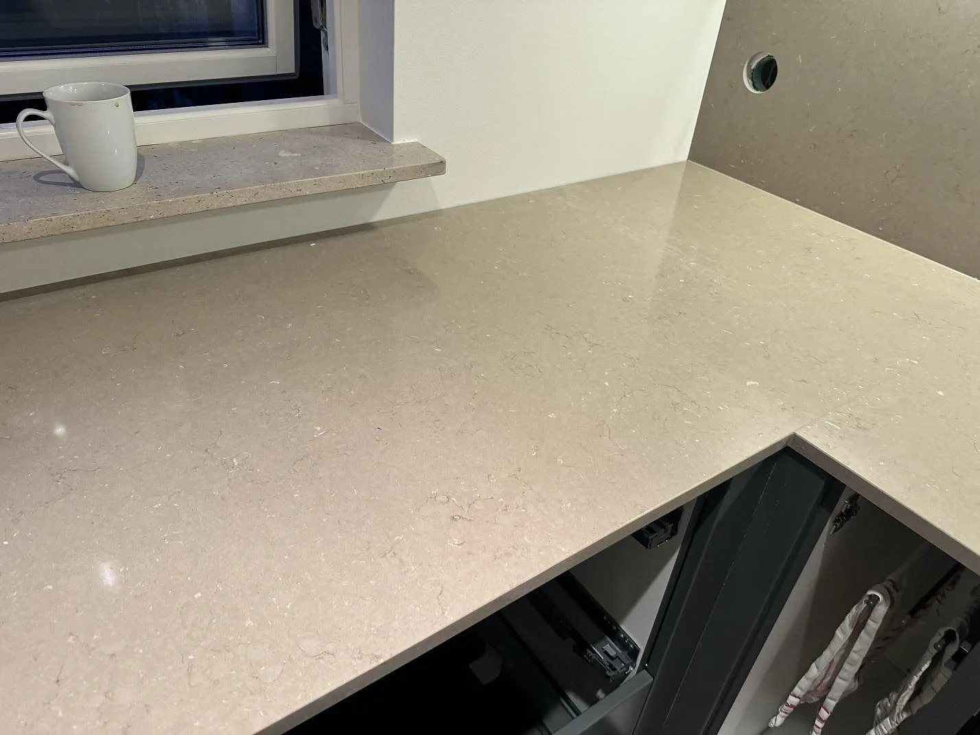 L-formad köksbänkskiva i polerad Silestone Coral Clay med fönsterbänk och väggpanel i samma sten i Löddeköpinge.