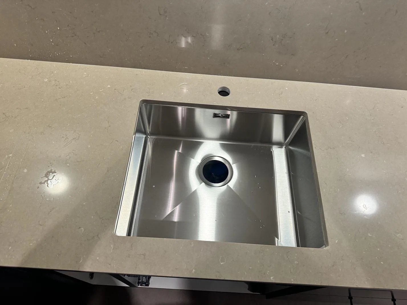 Närbild på rostfri diskho i polerad Silestone Coral Clay med blank kvartskomposityta och stänkskydd bakom i Löddeköpinge.