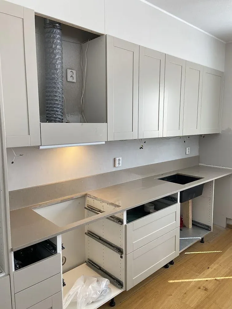 Greige Silestone Coral Clay köksbänkskiva med infälld svart induktionshäll och öppna köksstommar under montering i ett kök i Lomma.